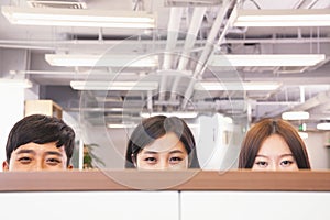 Office workers peeking over divider in office