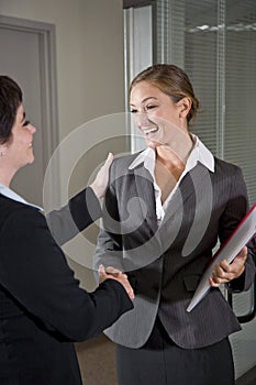 Office workers shaking hands at door of boardroom