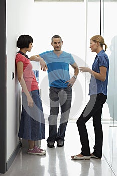 Office Workers Talking By Water Cooler In Hallway