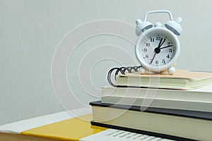 Office workload concept - stack of book with clock on the top
