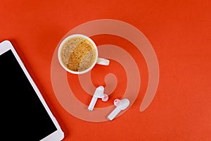 Office workplace with digital tablet PC on a wireless headphones a cup of coffee on red background