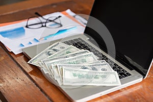 Office workplace with laptop and cash on wood table