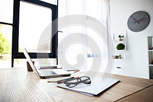 Office workplace with laptop and smart phone on wood table.