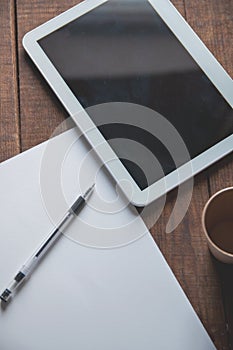 Office workplace with tablet pc on the table. On the table there is a tablet and a white sheet of paper with a pen