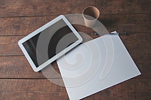 Office workplace with tablet pc on the table. On the table there is a tablet and a white sheet of paper with a pen