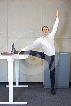 Office yoga - business man exercising at high desk