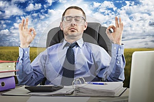 Office Zen. Relaxed Male Businessman Meditating At Workplace, Coping With Stress At Work, Sitting At Desk With Eyes Closed Against