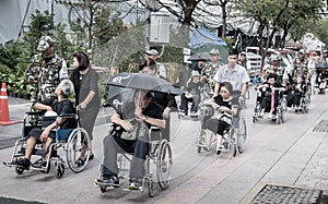 Officer help senior on wheelchair to devotions for funeral of King Rama IV at Grand Palace