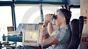 Officer during navigational watch looking through binoculars
