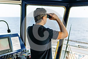 Officer during navigational watch looking through binoculars