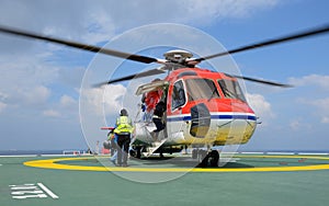 The officer take care passenger to embark helicopter at oil rig