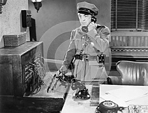 Officer talking on a telephone next to a switchboard photo