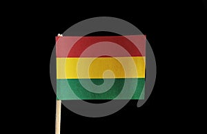 A official flag of Bolivia on toothpick on black background. A horizontal tricolor of red, yellow and green with the national coa photo