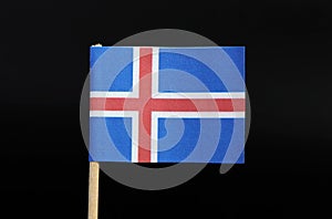 A official flag of Iceland on toothpick on black background. A blue field with the white-edged red Nordic cross that extends to