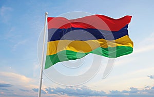 official flag of Mauritius at cloudy sky background on sunset, panoramic view. patriot and travel concept. copy space for wide