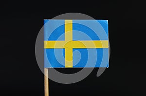 A official flag of Sweden on toothpick on black background. A blue field charged with a yellow Nordic cross that extends to the