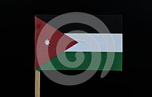 A official and unique flag of Jordan on toothpick on black background. A horizontal triband of black, white and green; with a red photo