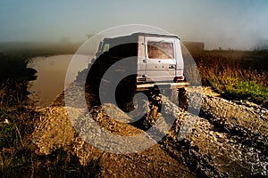 Offroad car on bad road. Water splash in off-road racing. Wheel close up in a countryside landscape with a muddy road.