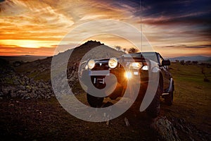 Offroad car on mountain road at sunset