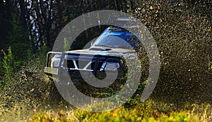 Offroad race on fall nature background. SUV or offroad car on path covered with grass crossing puddle with dirt splash