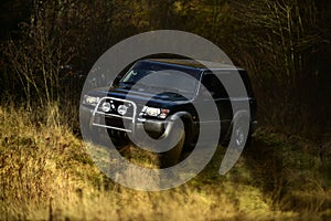 Offroad race on fall nature background. SUV or offroad car stuck in rut. Car racing in autumn forest. Extreme, obstacles