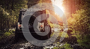 Offroad vehicle driving through the mud towards the setting sun