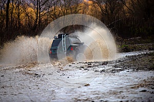 Offroading. Scene of wather splash in off-road racing. A car during a tough off-road competition diving in a muddy pool