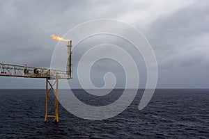 Offshore oil and gas flare blowout in the sea during storm background.