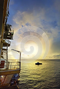 Offshore oil platform in evening.Among beautiful sunset.Crude oil is sucked up from the depths of the sea and manufacture or