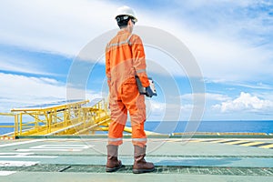 An offshore oil rig worker wearing personal protective equipment and standing on offshore wellhead remote platform