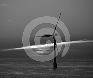 Offshore turbine and sun behind the clouds at dawn