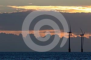 Offshore wind farm turbines silhouette at sunrise or sunset