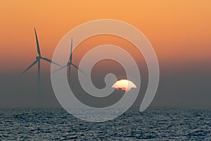 Offshore wind turbines. Misty morning sea sunrise. Tropical back