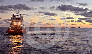 Offshore workboat moves toward Derrick barge and other vessels on Bass Strait Australia at sunset.