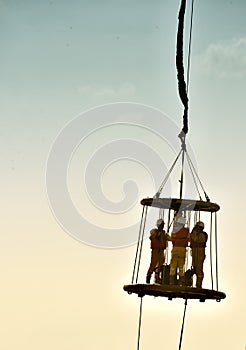 Offshore worker inside personal safety basket hanging in the air