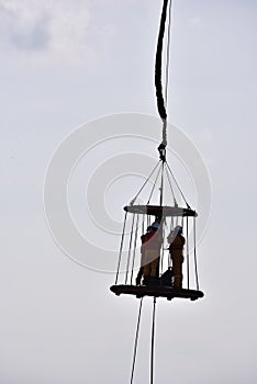 Offshore worker inside personal safety basket hanging in the air