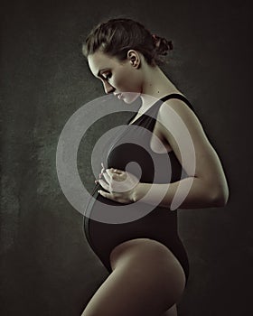 Offspring. Pregnant woman posing in studio.