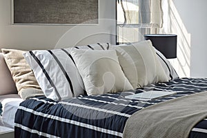 Offwhite and striped pillows on bed photo