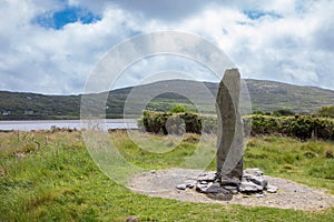 Ogham Stone in Irish Landscape Under Cloudy Blue Sky