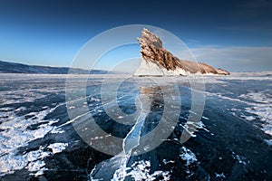 Ogoy island on winter Baikal lake with transparent cracked blue ice