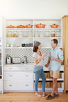 Oh look, its coffee o clock. a happy married couple enjoying a cup of coffee together in their kitchen at home.