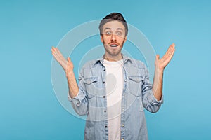 Oh my god, wow! Portrait of astonished man in denim shirt raising hands in amazement, looking with open mouth