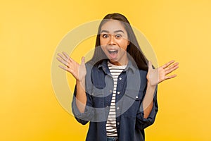 Oh my god, wow! Portrait of excited shocked girl in denim shirt standing with raised hands and shouting in amazement