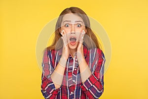 Oh my god, wow! Portrait of shocked amazed ginger girl in checkered shirt looking at camera with open mouth and surprised big eyes