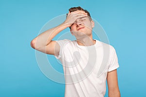 Oh no, I forgot! Portrait of unlucky man in casual white t-shirt making facepalm gesture, feeling regret