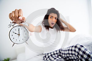 Oh no it`s 10 o`clock. Profile photo of crazy mad curly dark skin lady sitting bed sheets holding metal alarm clock