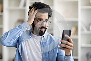 Oh No. Shocked Indian Guy Looking On Smartphone Screen And Touching Head