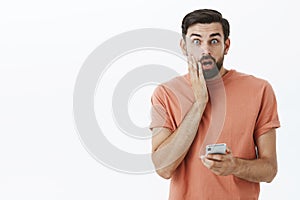 Oh no, wrong number. Portrait of man accidently sent message via smartphone wrong person touching face and open mouth photo