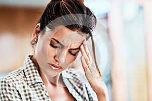 Oh this is a terrible migraine. an attractive young woman suffering with a headache at home.