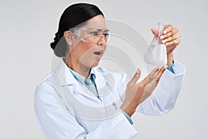 Oh wow, I did not expect that. an attractive young female scientist looking shocked while examining a beaker filled with